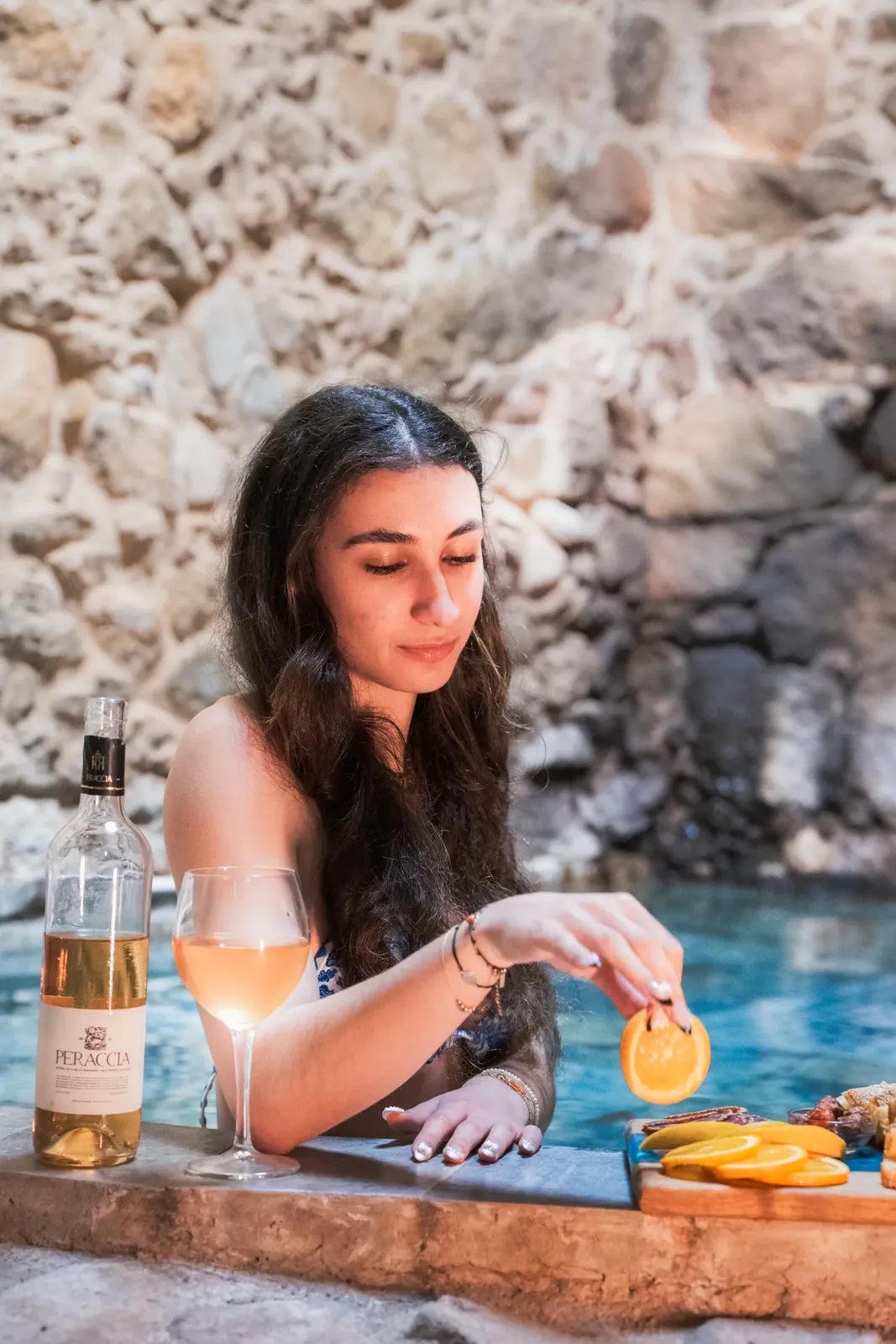 Une baigneuse dans l’eau chaude naturelle, un verre sur la margelle